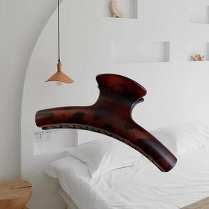 Large 15cm tortoise shell hair claw clip shown in a minimalist white bedroom setting