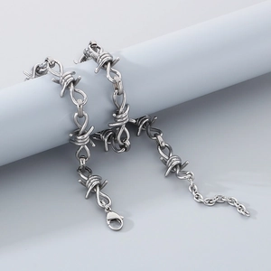 Close-up of silver punk barbed wire necklace with lobster clasp on a grey stand
