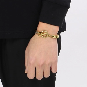 Bracelet chaîne hip-hop dorée avec texture rayée et fermoir en T porté sur le poignet