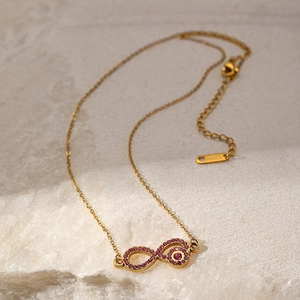 Gold infinity necklace for women with pink zircon pendant on white marble stone