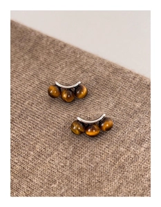Detailed macro shot of tiger eye stone earrings on a brown knitted fabric texture
