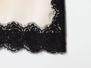 Détail du tissu satiné champagne avec bordure en dentelle de cils noire délicate