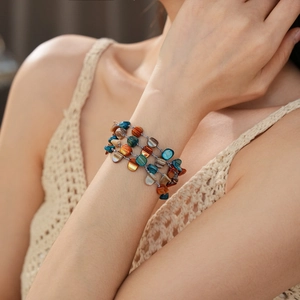 Detail of bohemian multilayer bracelet with colorful irregular shell stones on wrist