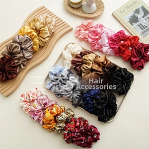 Close-up of assorted satin scrunchies in solid colors and patterns on a wooden tray