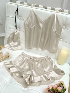 Close-up of champagne silk satin pajama set with ruffles and matching storage bag