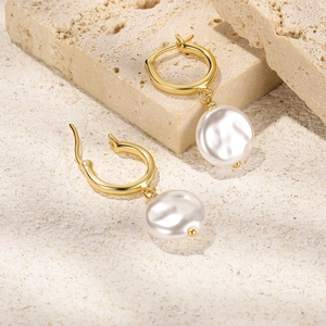 Detailed view of elegant gold drop earrings featuring natural flat pearls on stone