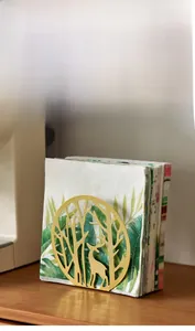 Detailed close-up of golden metal napkin holder with forest and deer cutout design