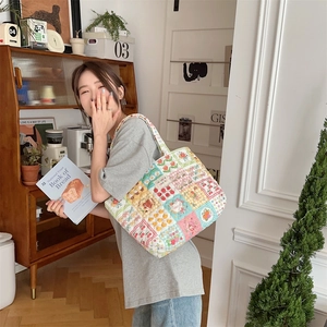 Detail of colorful patchwork quilted tote bag with stitched grid pattern on the fabric
