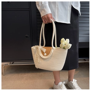 Detail of straw woven tote with brown leather flap, pearl button, and lace bow decoration