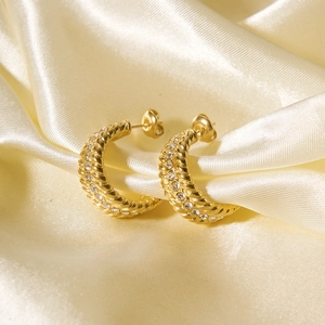 Detail of gold C-hoop earrings with twisted texture and crystal rhinestones on silk
