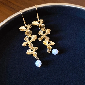 Vue macro détaillée de boucles d'oreilles dorées en forme de feuilles avec perles bleues
