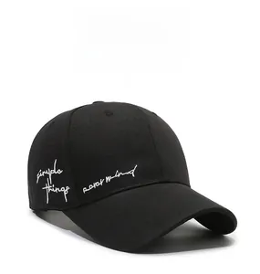 Detail of white cursive embroidery on a black twill cotton baseball cap side