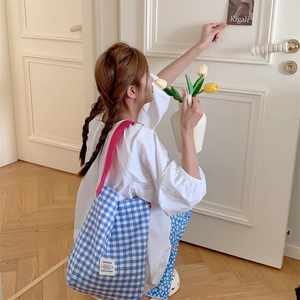 Détail du sac cabas en toile à carreaux bleu et blanc avec bandoulière rose et étiquette