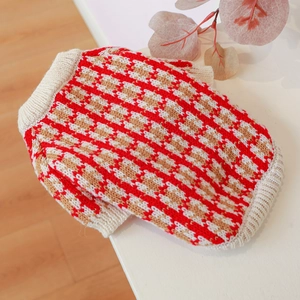 Close-up of red and white houndstooth knit pet sweater with ribbed collar details