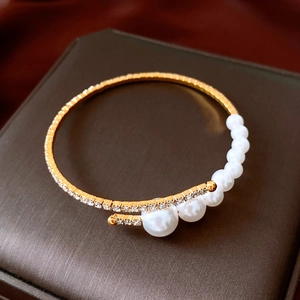 Close-up of golden wrap bracelet with gradient pearls and sparkling rhinestone details