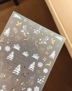 Détail de stickers à ongles 3D de Noël avec rennes dorés et flocons de neige blancs