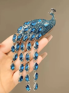 Close-up of a silver peacock brooch with blue rhinestones and long tassel details