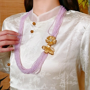 Detail of multi-layer purple seed bead necklace with gold floral butterfly pendant