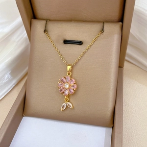 Macro shot of pink zircon flower pendant with golden chain in a luxury jewelry gift box