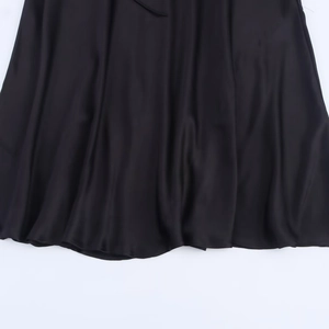 Detailed close-up showing the elegant drape and glossy texture of black satin dress fabric