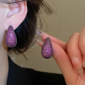 Close-up of a model wearing elegant magenta pear-cut zircon drop earrings with metal base