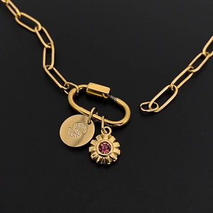 Gold-plated paperclip chain necklace featuring initial 'S' and pink gemstone floral charms