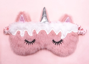 Detail of plush unicorn eye mask featuring silver horn and pink sequin ears on furry texture