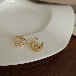 Detail of gold multi-layer pearl ear cuff set with zirconia on white ceramic tray