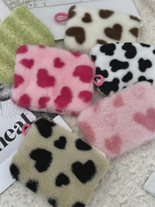 Variety of plush heart-shaped makeup pouches and mini coin purses on soft white rug