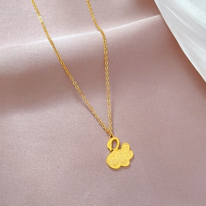 Close-up of golden hollow swan pendant on a fine chain over elegant silk fabric