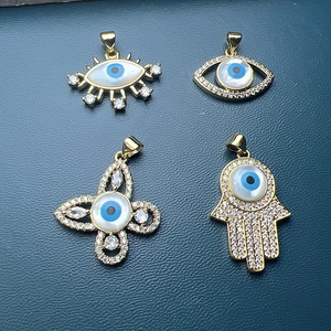 Gold Evil Eye charms set with mother of pearl and zircon stones on blue background