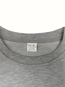 Gros plan du col de t-shirt gris montrant la texture et l'étiquette de taille M