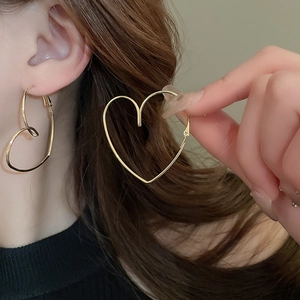 Detailed view of large gold heart-shaped hoop earrings on model for a minimalist style