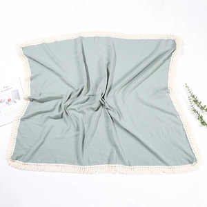 Dettaglio di una coperta per neonati in doppia garza di cotone verde salvia con nappe
