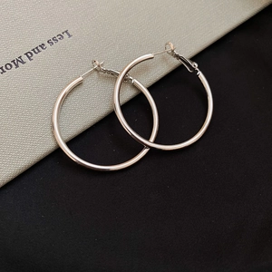 Close-up of sleek silver hoop earrings with a minimalist metallic finish and sharp detail