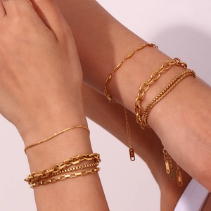 Detail of 18K gold-plated stainless steel chain bracelets layered on woman's wrist