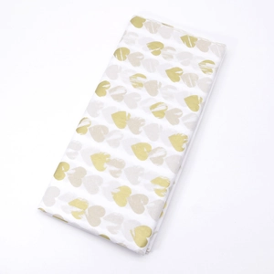 Detail of white tissue paper featuring gold and beige brushstroke heart patterns