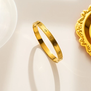 Gold titanium steel clover bangle with sparkling crystals and a secure clasp closure