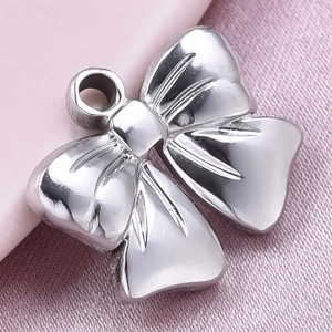 Detail of silver 304 stainless steel bow pendant on pink silk with textured engraving