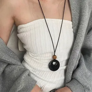Dettaglio della collana minimalista con pendente nero circolare e perla di legno
