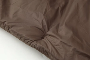 Détail de la texture matelassée marron foncé avec couture précise sur le bord du tissu