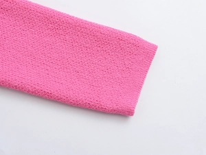 Detailed macro view of the fine pink knit texture and stitching on the cardigan sleeve