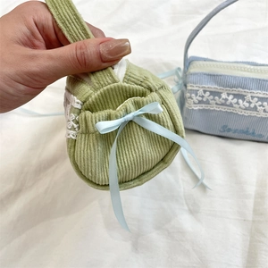 Detail der grünen Cord-Schreibwarentasche mit Spitzenbesatz und blauer Schleifendekoration