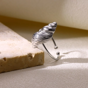Vue détaillée d'une bague coquillage en argent avec anneau réglable sur fond de pierre