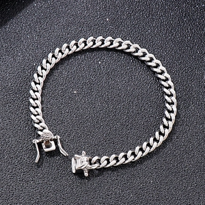 Detailed close-up of a silver Cuban link bracelet with square clasp on black texture