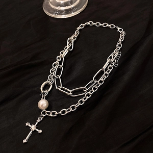 Détail du collier argenté double rang avec croix strassée et perle sur fond de soie noire