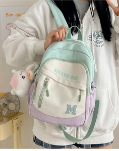 Front view of mint green school backpack featuring patch embroidery and a plush toy