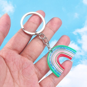 Sweet rainbow resin keychain with colorful dots and silver metal ring against a blue sky