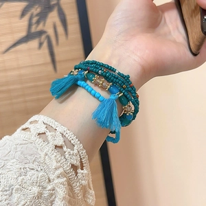 Detail of bohemian layered beaded bracelets with blue crystal beads and colorful tassels