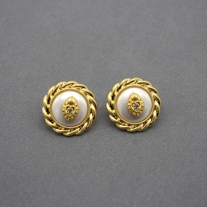 Detailed view of gold rope textured stud earrings with white mother of pearl and heart motif